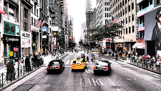 three yellow and black cars running on street near buildings thumbnail