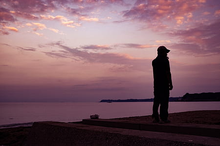 silhouette of man standing near body of water thumbnail