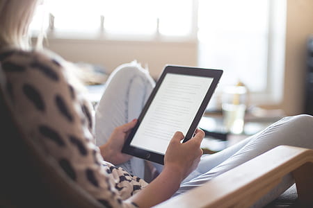 woman on brown armchair holding turned on white iPad thumbnail