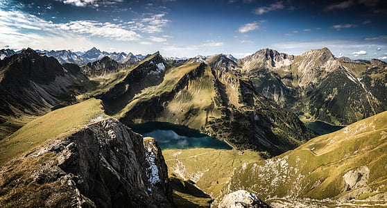 body of water between mountain under white cloudy sky thumbnail