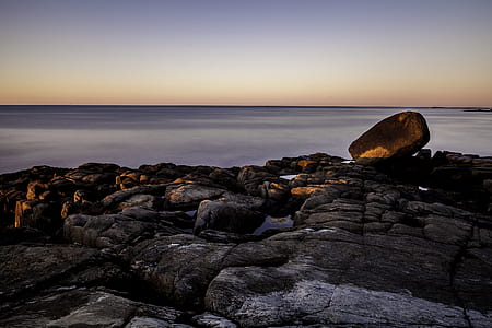 rock formation in front calm body of water thumbnail