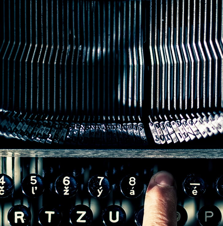 person pressing on typewriter key in close-up photography
