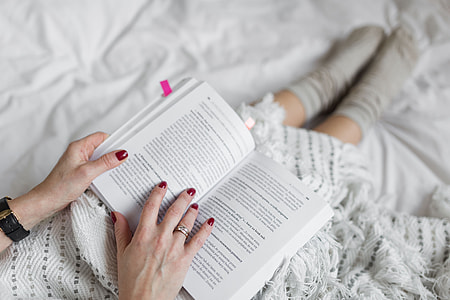 Soft photo of woman on the bed with the book and cup of coffee in hands thumbnail