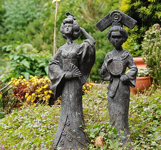 two women concrete statue at the garden near flowers thumbnail