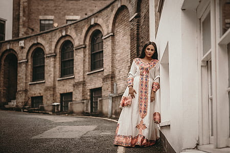 woman leaning on white and brown concrete building during daytime thumbnail