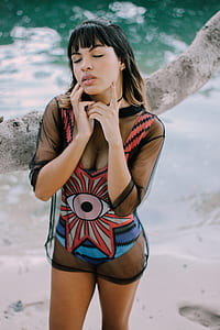 woman in red and white swimsuit leaning on gray tree trunk thumbnail