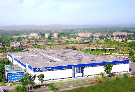 birds-eye view of white and blue building surrounded by trees thumbnail