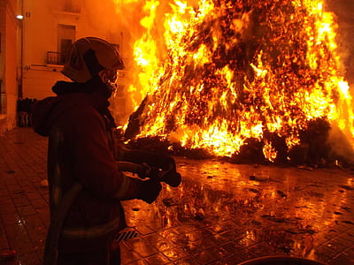 firefighter holding fire hose near fire thumbnail