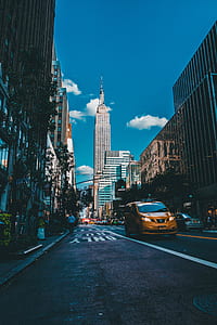 grey concrete buildings near vehicles under cloudy blue sky thumbnail