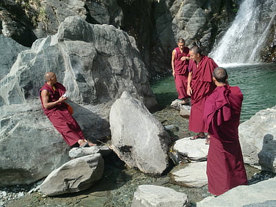 monks standing on rocks near body of water thumbnail