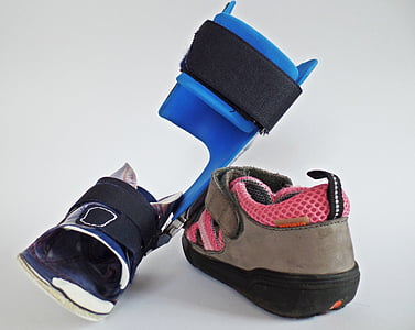 black and blue walking brace and brown and pink leather velcro-strap shoe thumbnail