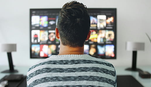 Man sitting in front of large television, browsing options. thumbnail
