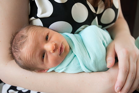 woman carrying a baby in teal swaddle thumbnail