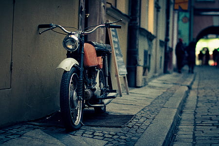 closeup photography of red and black standard motorcycle leaning on gray concrete wall thumbnail