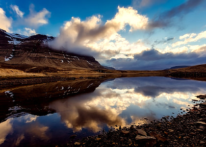 landscape photography of body of water beside mountain thumbnail