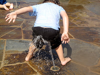 infant in black shorts playing with water sprinkler thumbnail