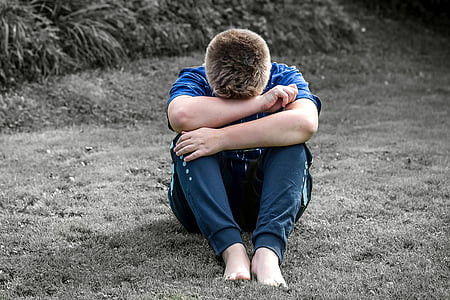 man wearing blue t-shirt and black pants sitting over grass field thumbnail