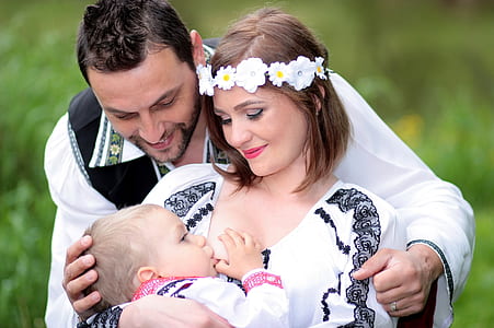 woman wearing flower headdress carrying baby at the back of man wearing white long-sleeved shirt thumbnail