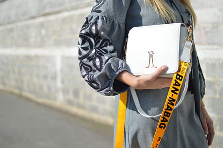 woman carrying leather bag near wall during day thumbnail