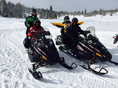 four person riding snowmobile during daytime thumbnail
