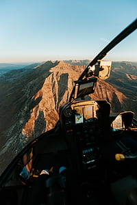 person riding helicopter over brown mountain thumbnail