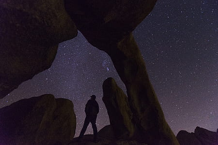 man standing under rock formation thumbnail