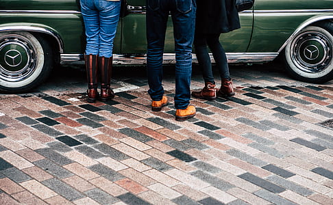 three person standing beside green car thumbnail