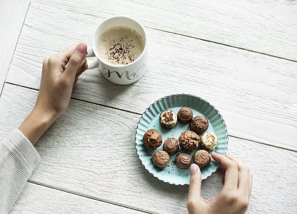 person holding chocolate and mug of coffee thumbnail