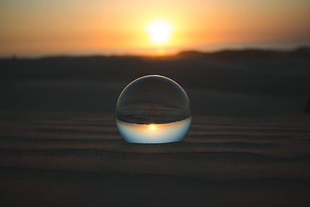 clear glass ball on brown sand thumbnail