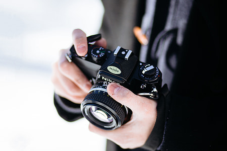 A photographer man holding a black retro camera thumbnail