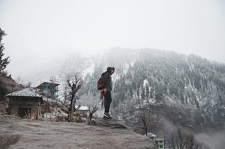 man standing on cliff near house thumbnail
