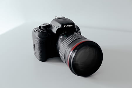 black Canon DSLR camera on white surface thumbnail