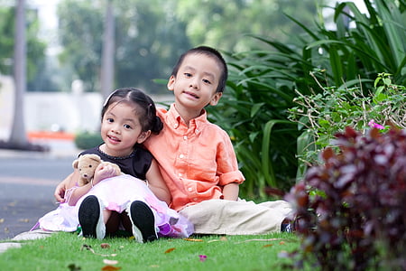 boy sitting beside smiling girl on grass lawn thumbnail