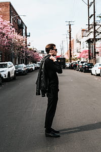 man holding black leather jacket standing on asphalt road outdoors thumbnail