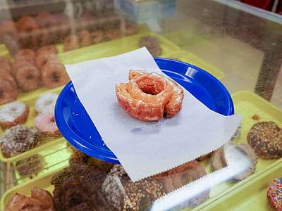Glazed cake donut sitting on a blue plate inside of a donut shop. thumbnail