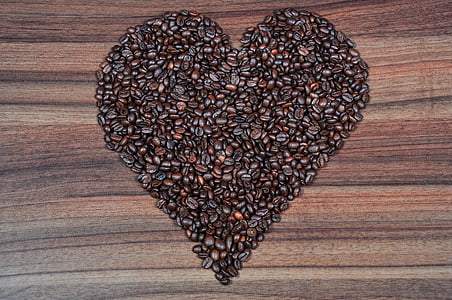 coffee beans in heart formation on brown wooden table thumbnail