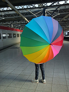 person standing while holding rainbow umbrella thumbnail
