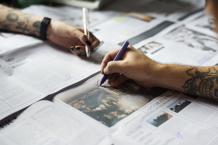 person writing on newspaper thumbnail