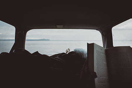 person reading book near body of water thumbnail