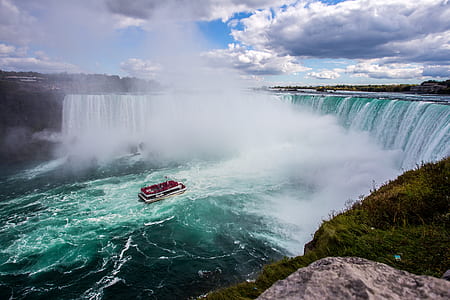boat on body of water in front of waterfalls thumbnail