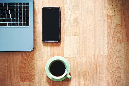 green ceramic mug filled with coffee on green saucer beside black Android smartphone thumbnail
