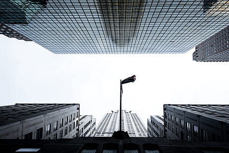 low angle view photography of flag pole between high-rise buildings thumbnail