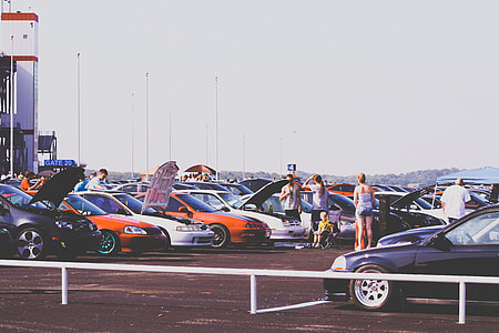 people standing next to vehicles in parking area during daytime thumbnail