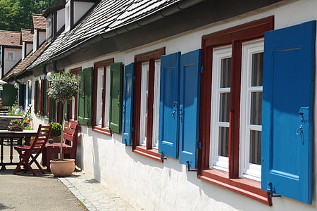 white concrete house with blue and red windows at daytime thumbnail