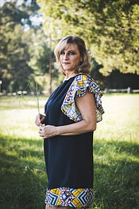 woman standing on grass near tall trees during daytime thumbnail