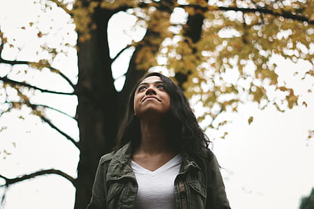 woman standing against trees looking up thumbnail