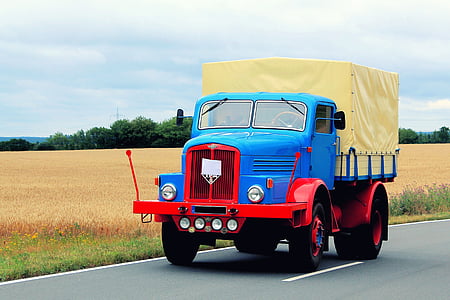blue, red, and beige truck on road near grass field during daytime thumbnail