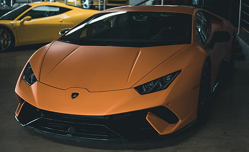 orange Lamborghini Huracan coupe parked inside garage beside yellow coupe thumbnail