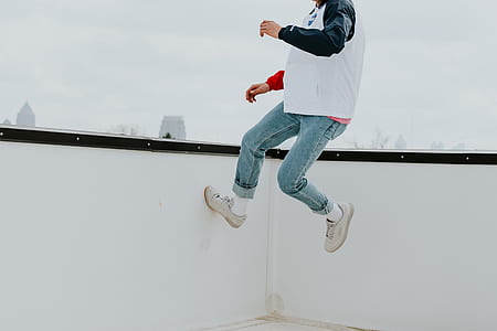 person jumping towards white wall during daytime thumbnail