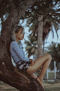 woman sitting on tree in selective focus photography thumbnail